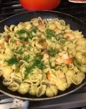 Pasta with shrimp and herbs in skillet.