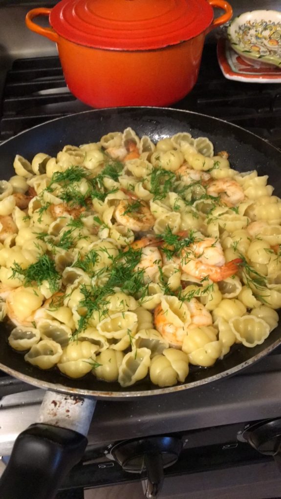 Shrimp pasta with herbs in a black skillet.