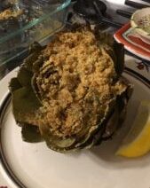 Stuffed artichoke on a plate with lemon.