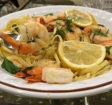 Shrimp pasta with lemon slices and herbs.