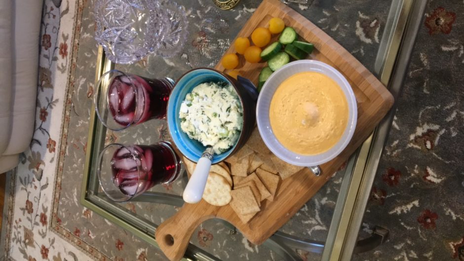 Cheese spread and dip with crackers and fruit on a wooden board.