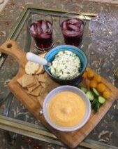 Cheese platter with drinks on table.