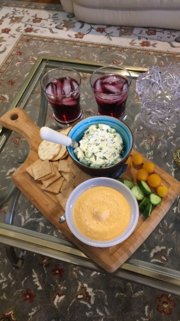 Cheese spread and dip with crackers and fruit on a wooden board.