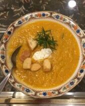 Bowl of soup with croutons and herbs.