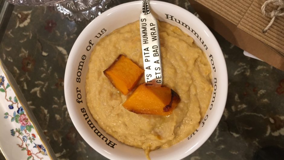 A bowl of hummus with a pita chip and a humorous label.