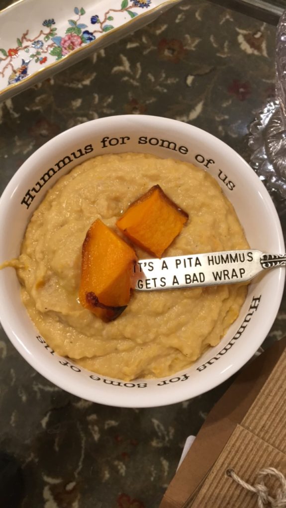 A bowl of hummus with a pita chip and a humorous label.