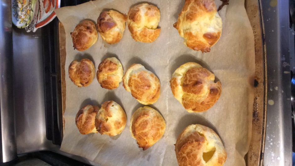 Freshly baked golden brown cheese rolls on parchment paper.