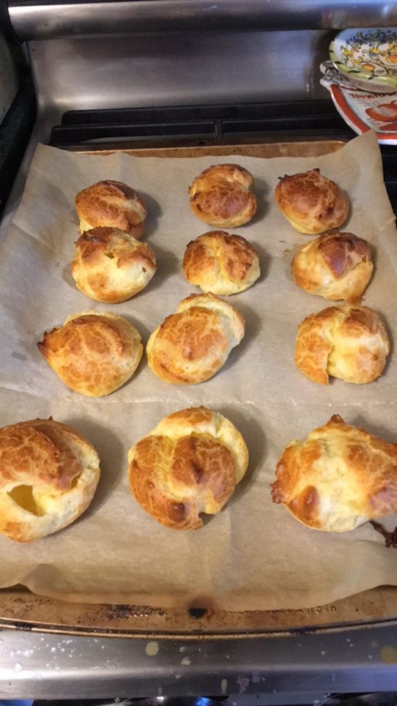 Freshly baked golden brown cheese rolls on parchment paper.