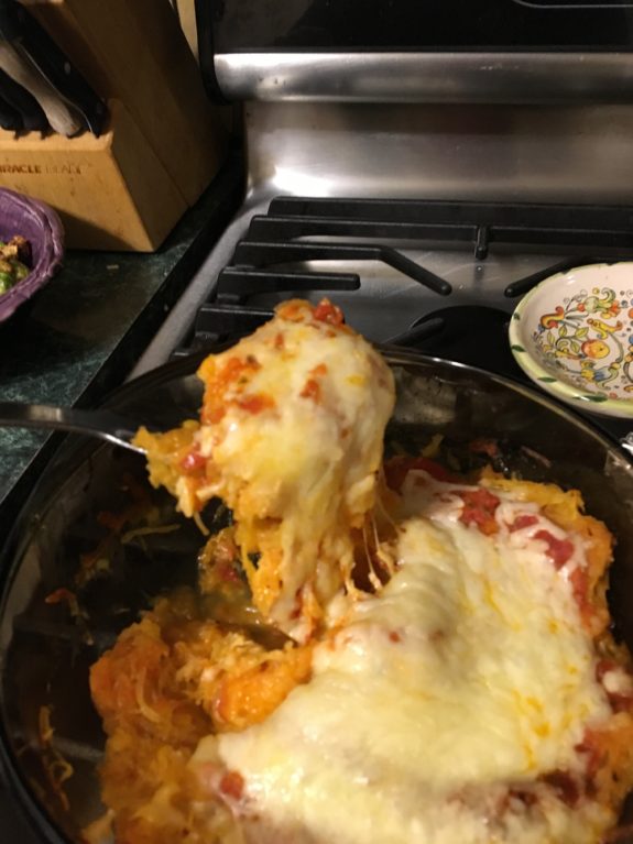 A cheesy slice of pizza being lifted from a pan.