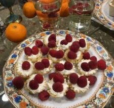 Plate of raspberry-topped desserts on table.