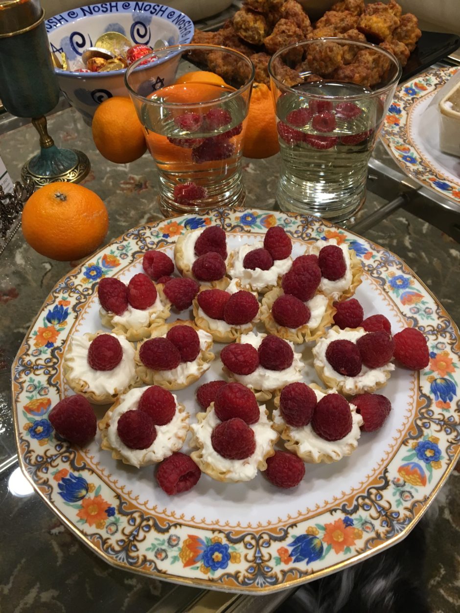 A plate of raspberry-topped cream cheese or dessert bites on a decorative plate.