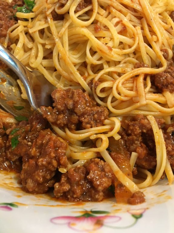 Close-up of spaghetti with meat sauce on a fork.