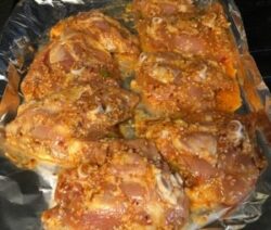 Marinated chicken pieces on foil-lined tray.
