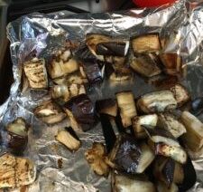 Roasted eggplant pieces on foil-lined tray.
