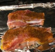 Seasoned salmon fillets on foil-lined tray.