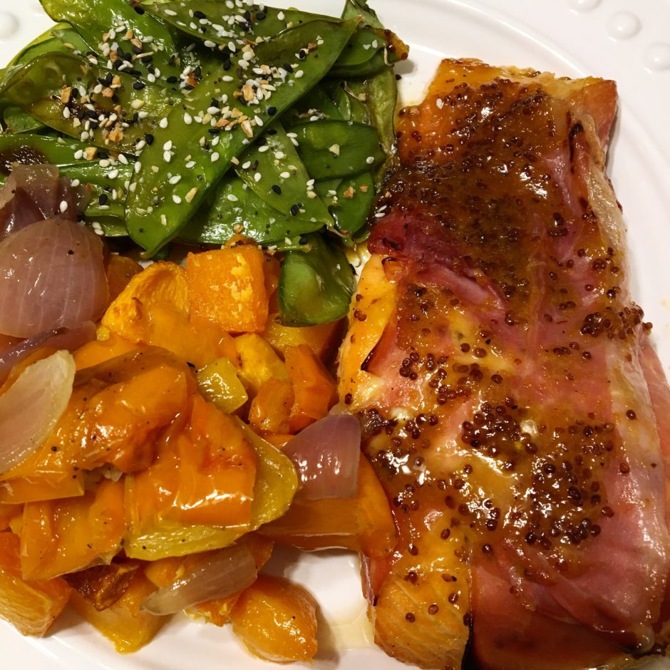 A plate with cooked salmon, sweet potatoes, and spinach.