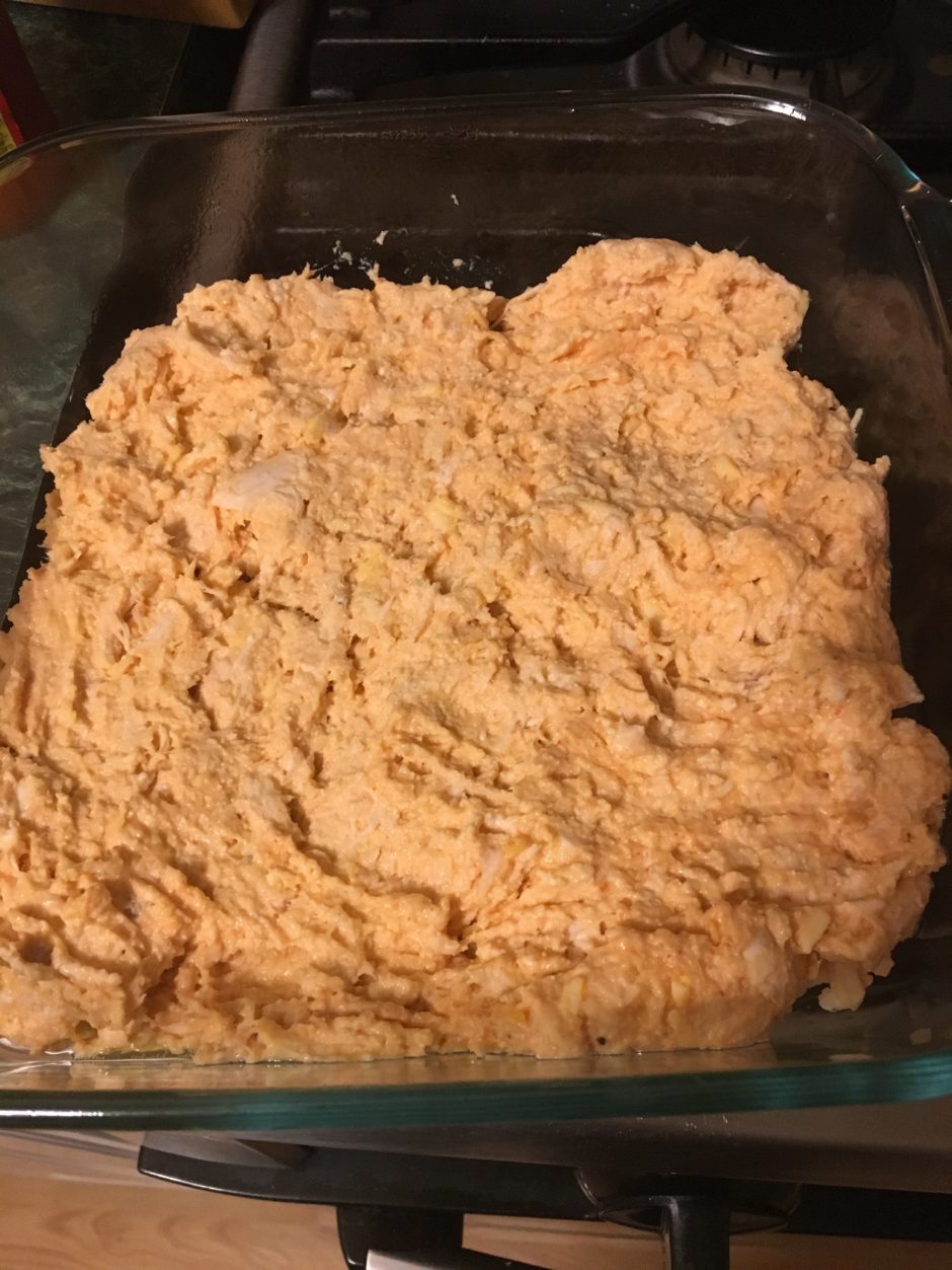 A glass dish filled with a creamy orange spread or mixture.