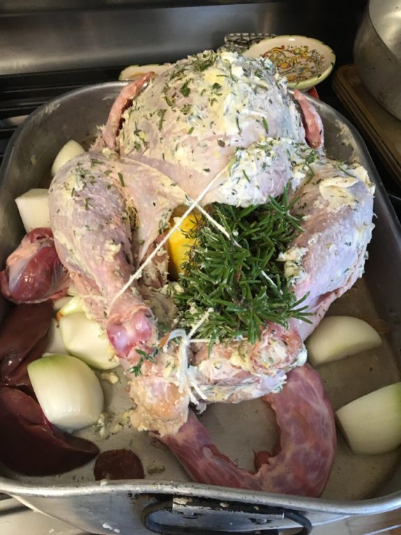 Raw whole chicken stuffed with herbs and onions, ready for cooking.