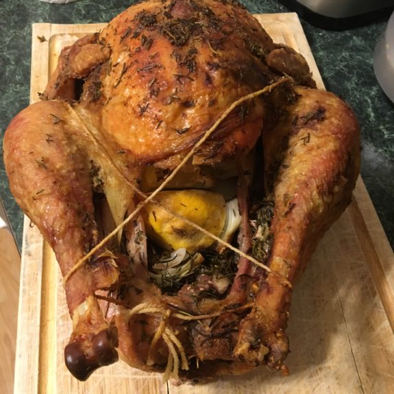 A roasted whole chicken stuffed and tied with kitchen twine.