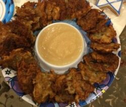 Latkes with applesauce on decorative plate.