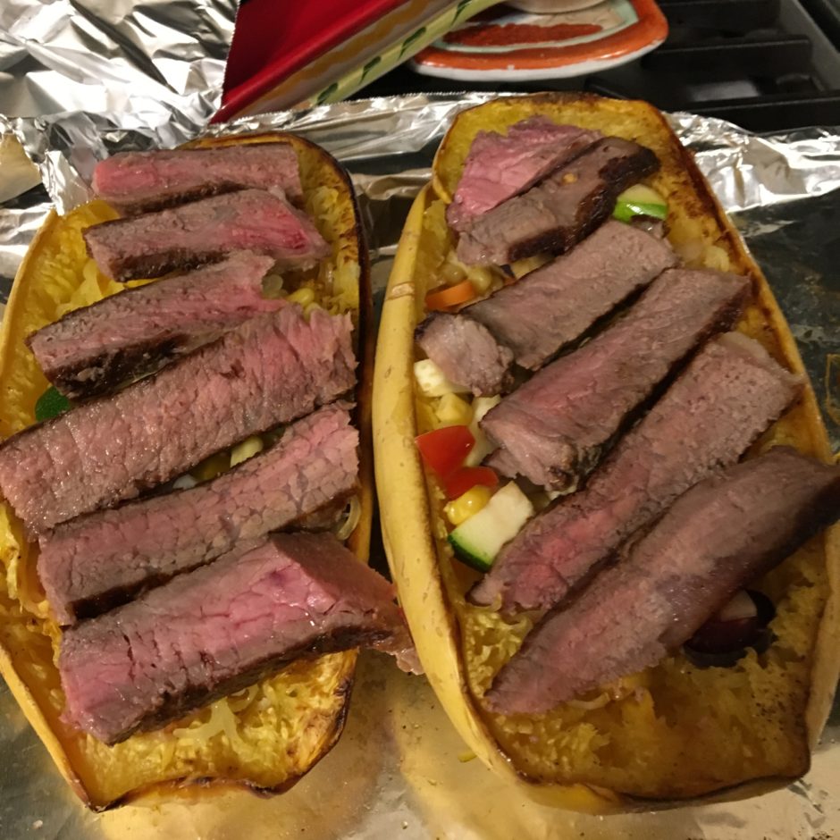 Two open-faced sandwiches topped with sliced steak and vegetables.
