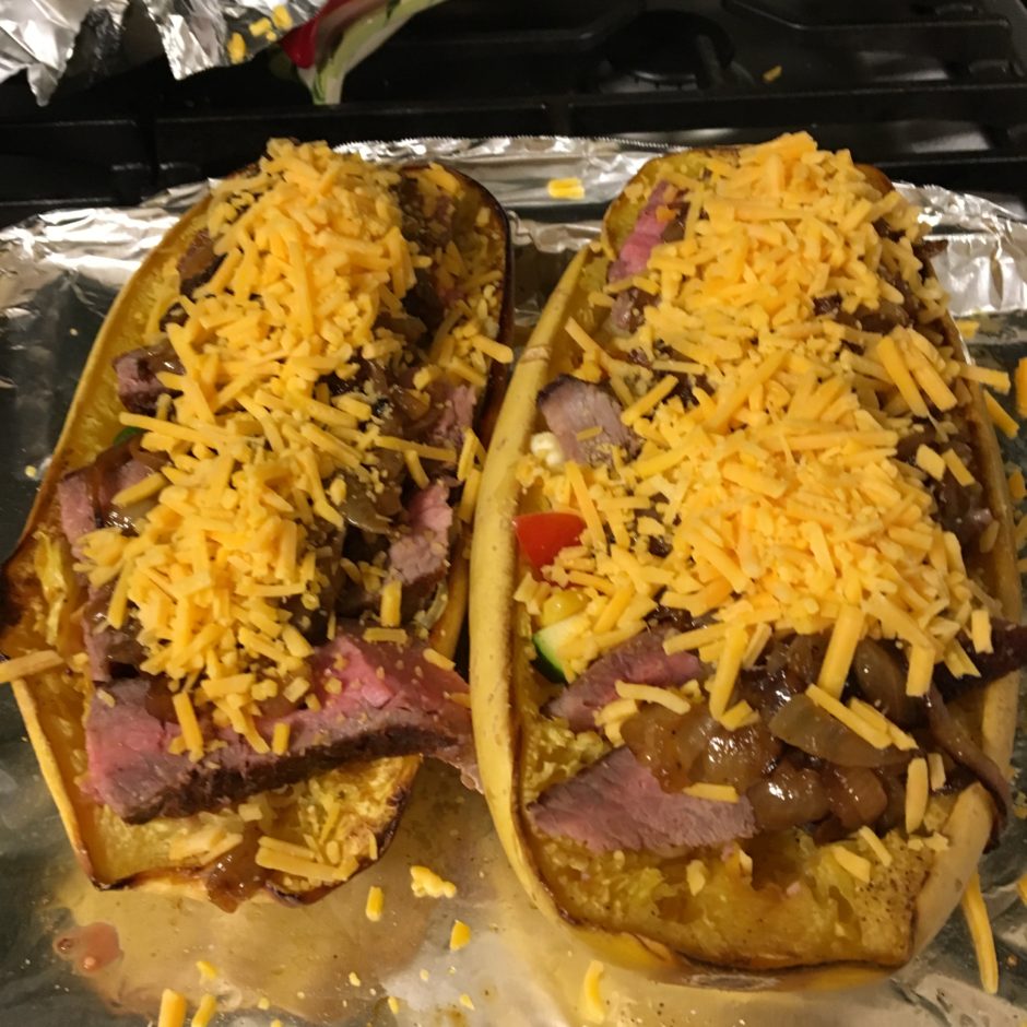 Two loaded hot dogs topped with shredded cheese on foil.