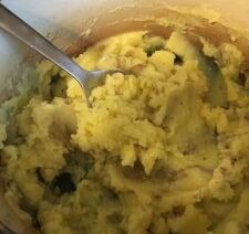 Mashed potatoes in a pot with spoon.