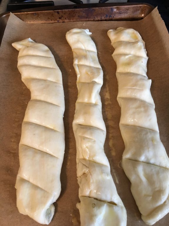 Three twisted dough ropes on a brown surface ready for baking.