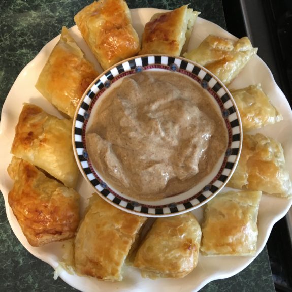 Plate of crescent rolls with a bowl of creamy dip in the center.