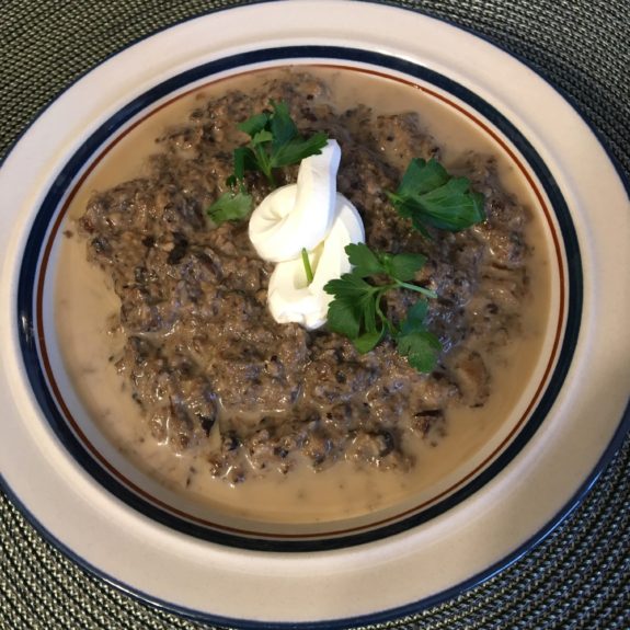 Creamy mushroom soup garnished with herbs and sour cream.