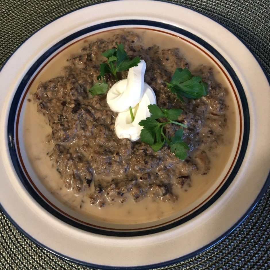 Creamy mushroom soup garnished with herbs and sour cream.