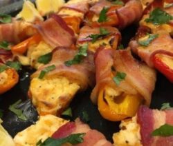 Bacon-wrapped stuffed peppers garnished with herbs.