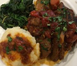 Mashed potatoes, cooked greens, and beef stew.