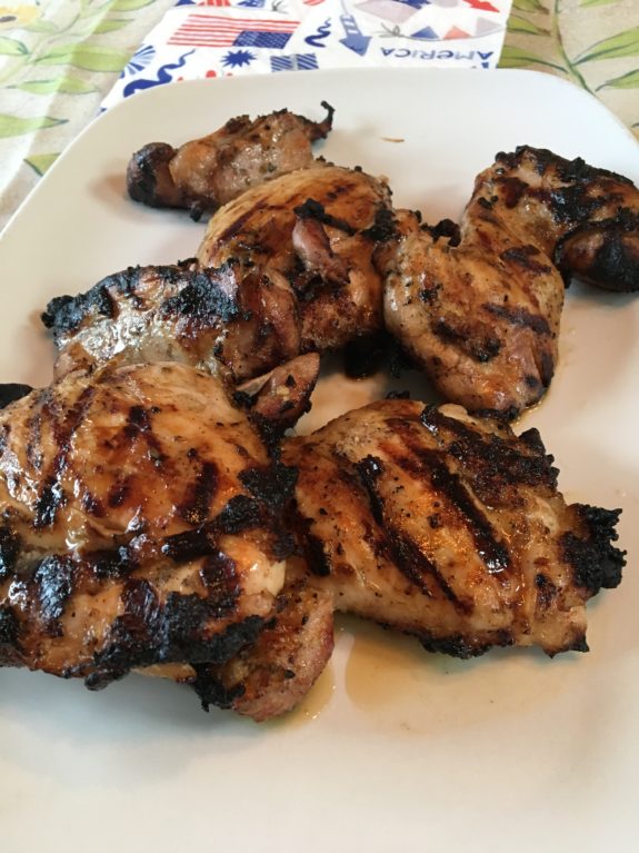 Grilled chicken thighs with char marks on a white plate.