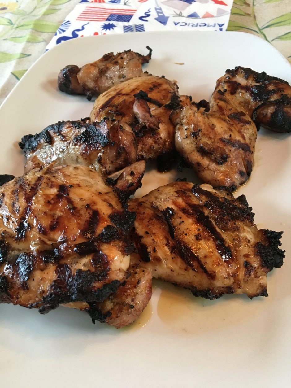 Grilled chicken thighs with char marks on a white plate.