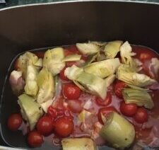 Artichokes and tomatoes in cooking pot.