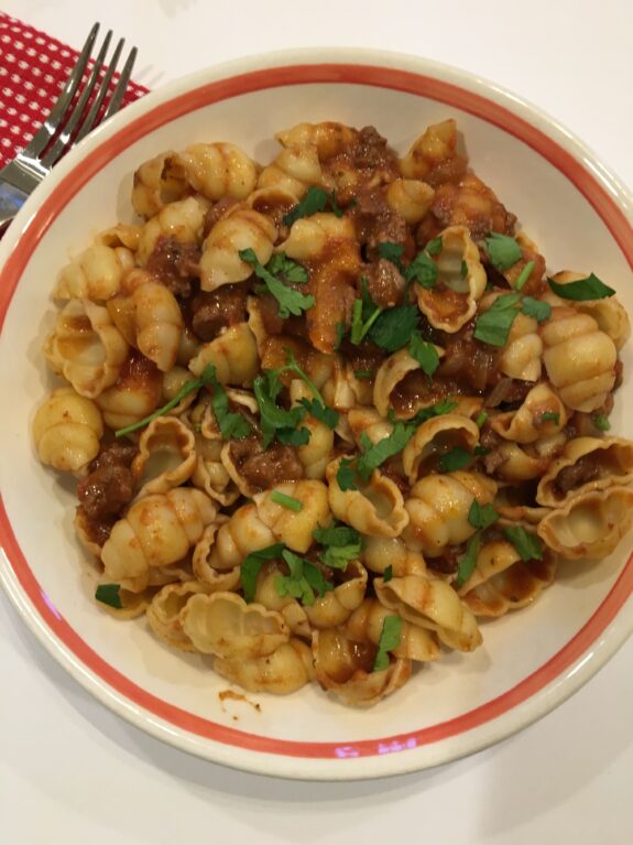 Plate of fried potato gnocchi garnished with herbs.