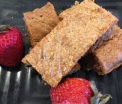 Brownies and strawberries on a black plate.
