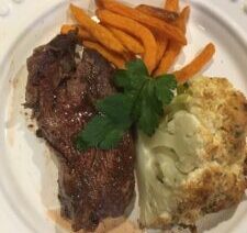 Steak, sweet potato fries, cauliflower on plate.