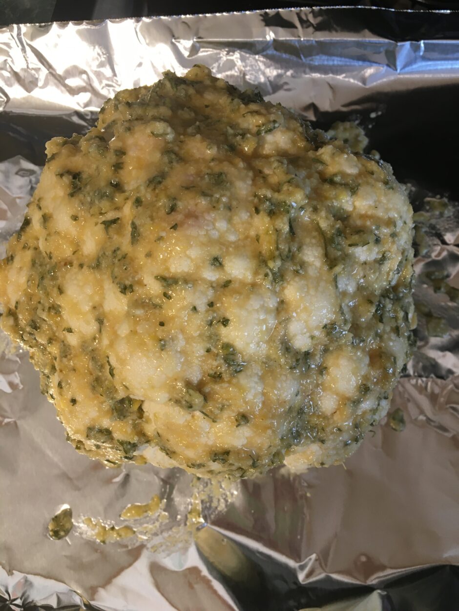 A seasoned cauliflower head covered with herbs and spices.