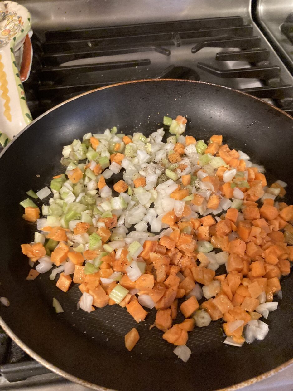 Diced carrots, celery, and onions cooking in a pan.