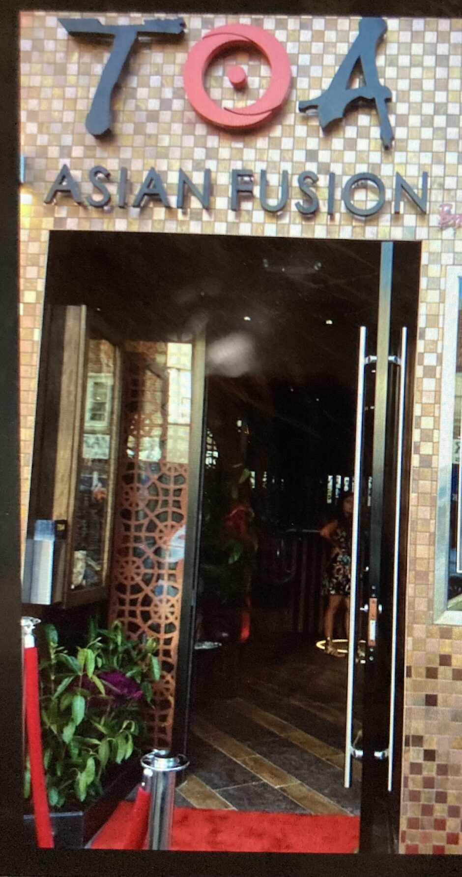 Entrance to a restaurant with glass doors and a tiled wall.