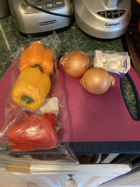 Fresh vegetables and cream cheese on a kitchen cutting board.
