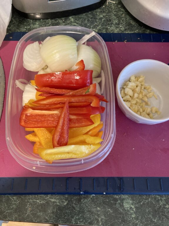 Chopped onions, bell peppers, and garlic prepared for cooking.