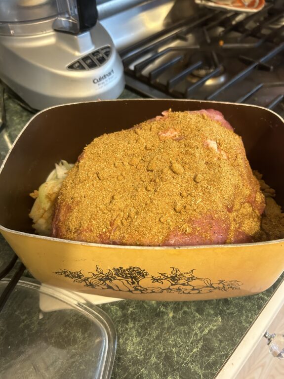 A breaded piece of raw meat in a vintage roasting pan.