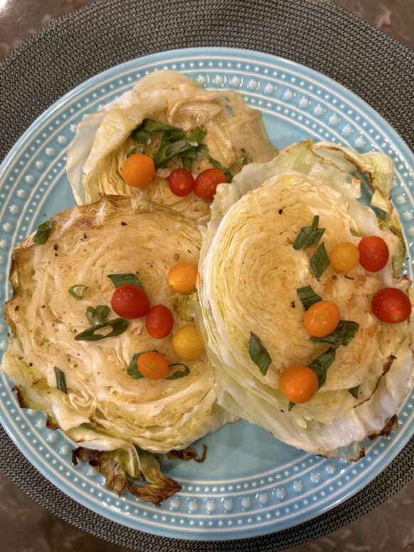 Three savory stuffed pastry shells with cherry tomatoes and herbs on a blue plate.